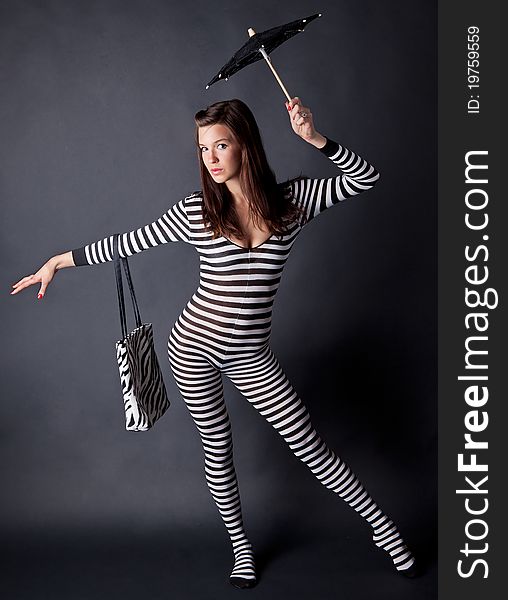 A portrait of a gorgeous young model, wearing a striped bodysuit and holding a matching purse and parasol. A portrait of a gorgeous young model, wearing a striped bodysuit and holding a matching purse and parasol