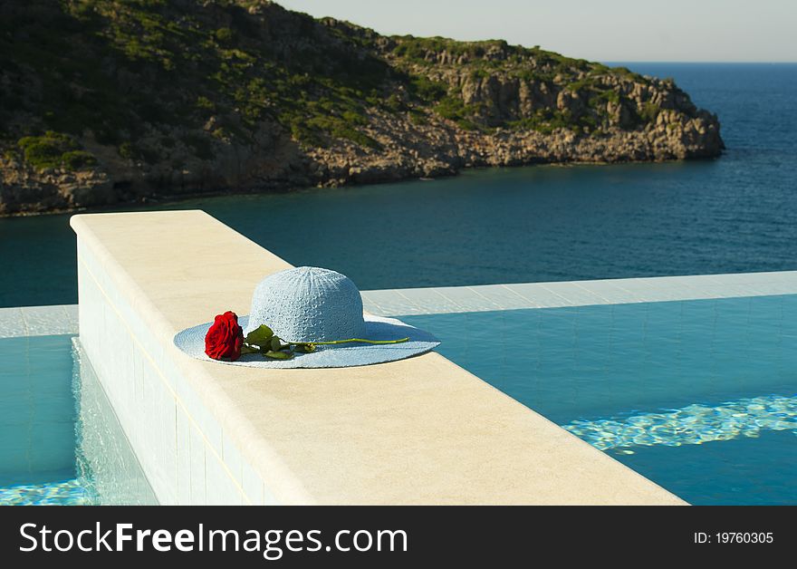 Blue hat and red rose near swimming pool in luxury mediterranian hotel.Crete. Blue hat and red rose near swimming pool in luxury mediterranian hotel.Crete
