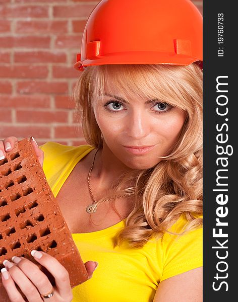 Pretty girl with helmet holding a brick. Pretty girl with helmet holding a brick