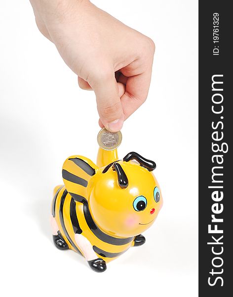 Droping a coin into a bee shaped piggy bank. Droping a coin into a bee shaped piggy bank