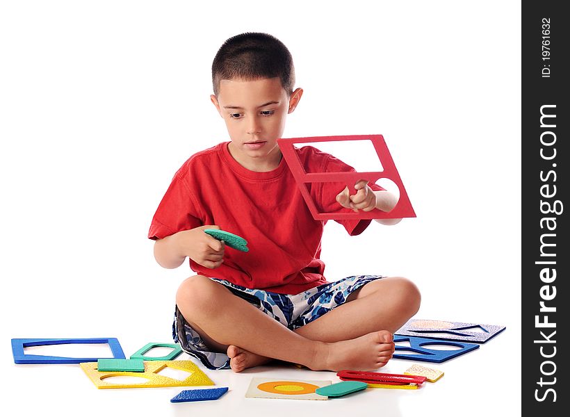 A kindergarten boy attempting to match colorful shapes with puzzel frames. Isolated on white. A kindergarten boy attempting to match colorful shapes with puzzel frames. Isolated on white.