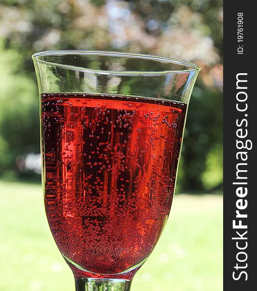 Sweet raspberry soda in a transparent glass on the terrace