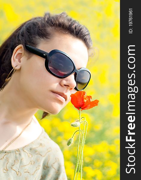 Brunette girl smelling a corn poppy from her hand