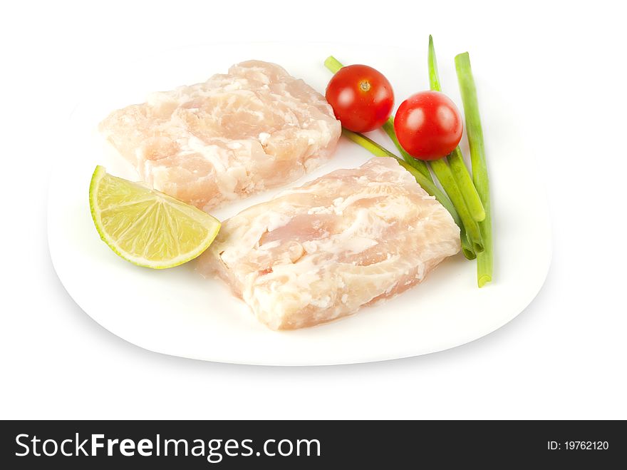 Pangasius fillet molded, decorated with cherry tomatoes with lime and green onions on a white plate