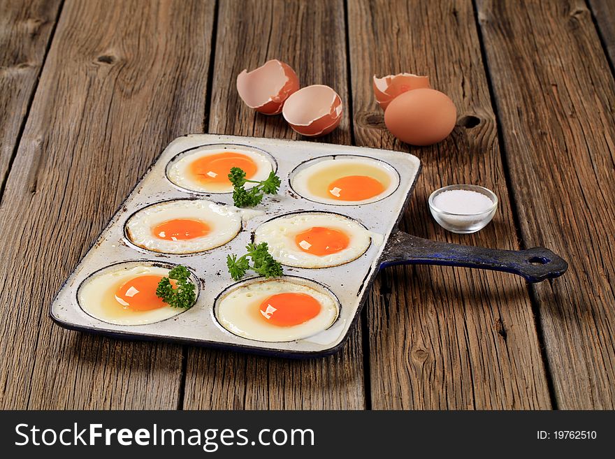 Six fried eggs in an old pan