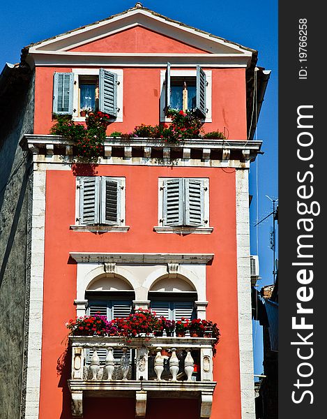 Tall old European house with red walls and stone balcony