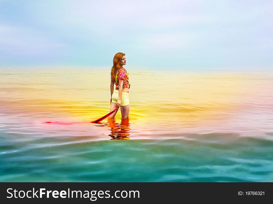 Beautiful sensual woman with red hair in colorful clothes standing and dreaming in the sea. Beautiful sensual woman with red hair in colorful clothes standing and dreaming in the sea