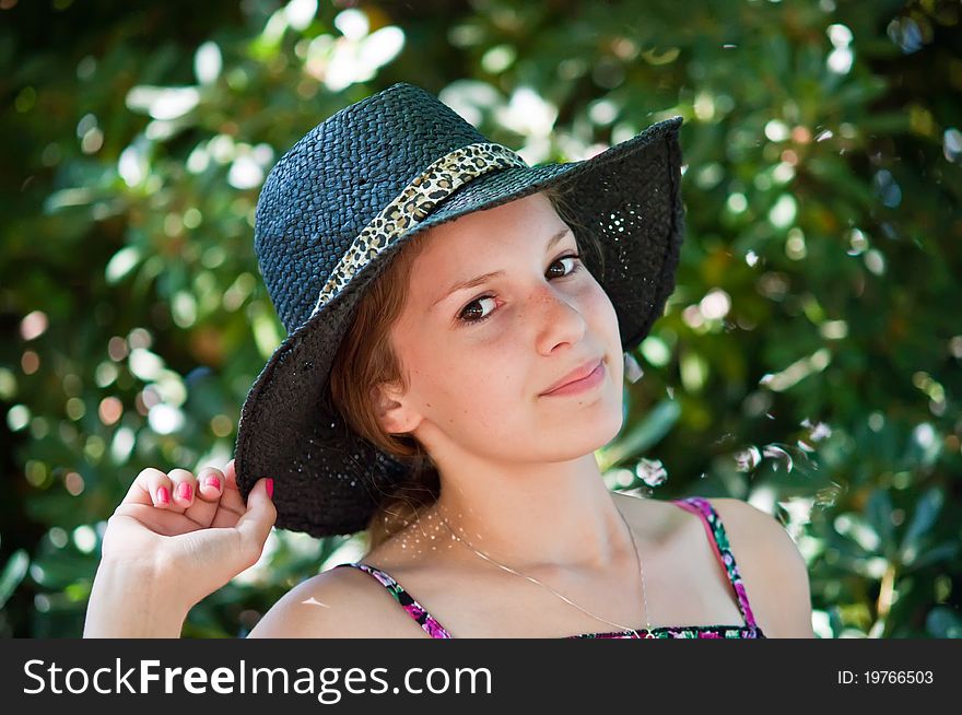 Portrait of teen girl in a black hat against the backdrop of the garden. Portrait of teen girl in a black hat against the backdrop of the garden.