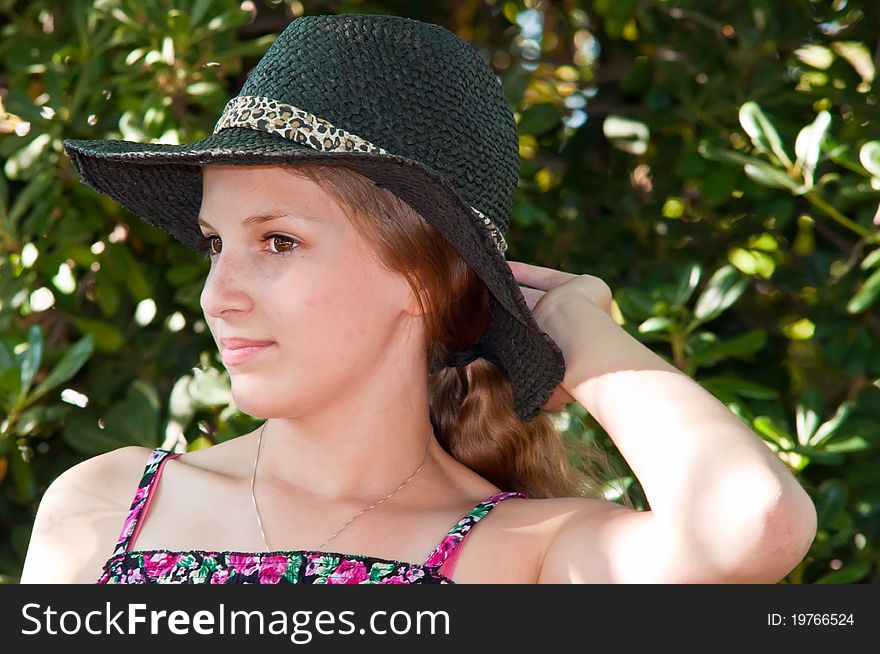 Portrait of teen girl in a black hat against the backdrop of the garden. Portrait of teen girl in a black hat against the backdrop of the garden.