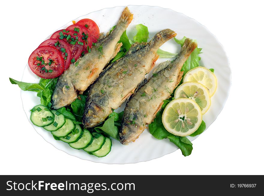 Fried fish with vegetables on white plate