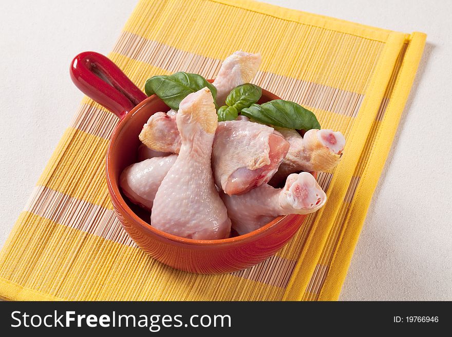 Raw chicken drumsticks in a pan