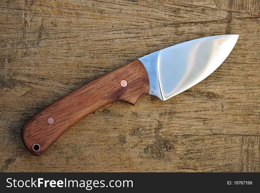 Hand made hunting knife on wooden background