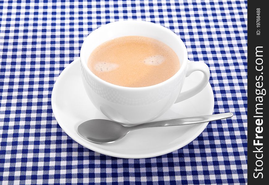 Cup coffee with foam on tablecloth
