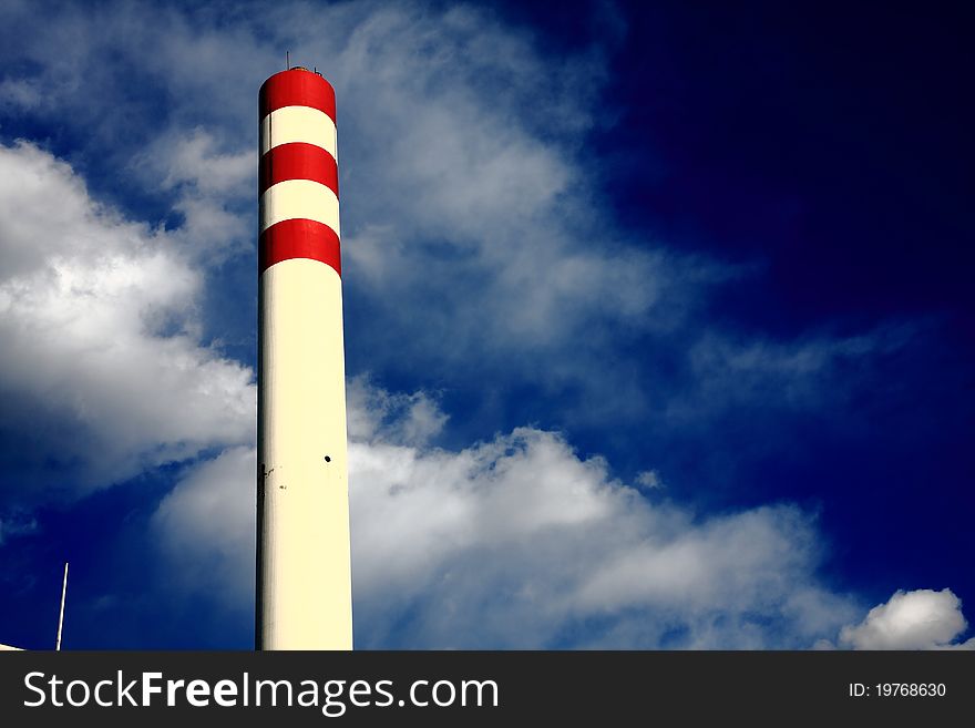 Chimney with red circle under blue sky on the factory