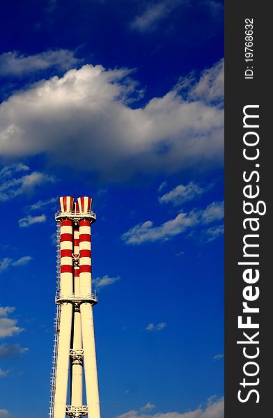 Chimney with red circle under blue sky on the factory