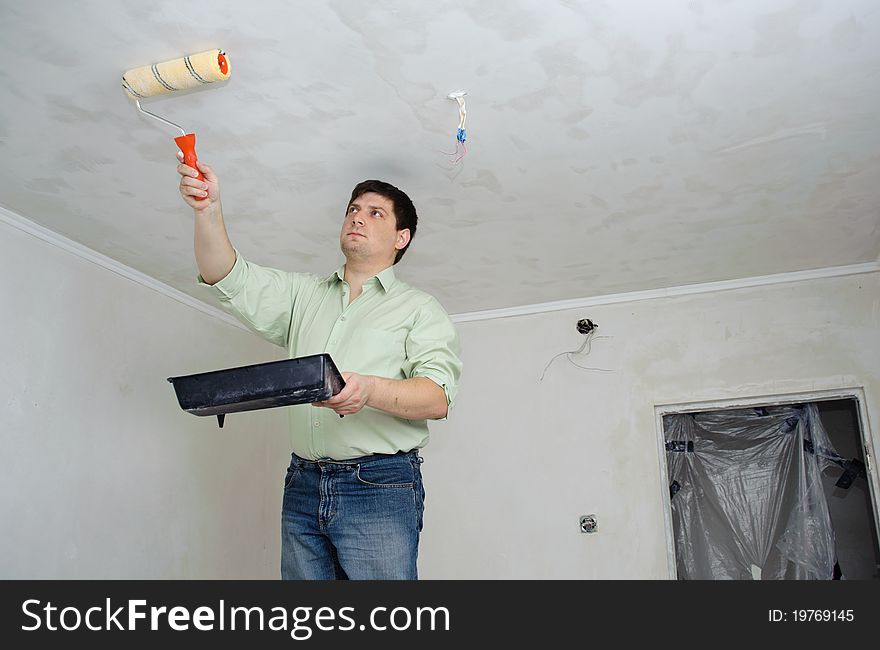 An image of a man painting the ceiling