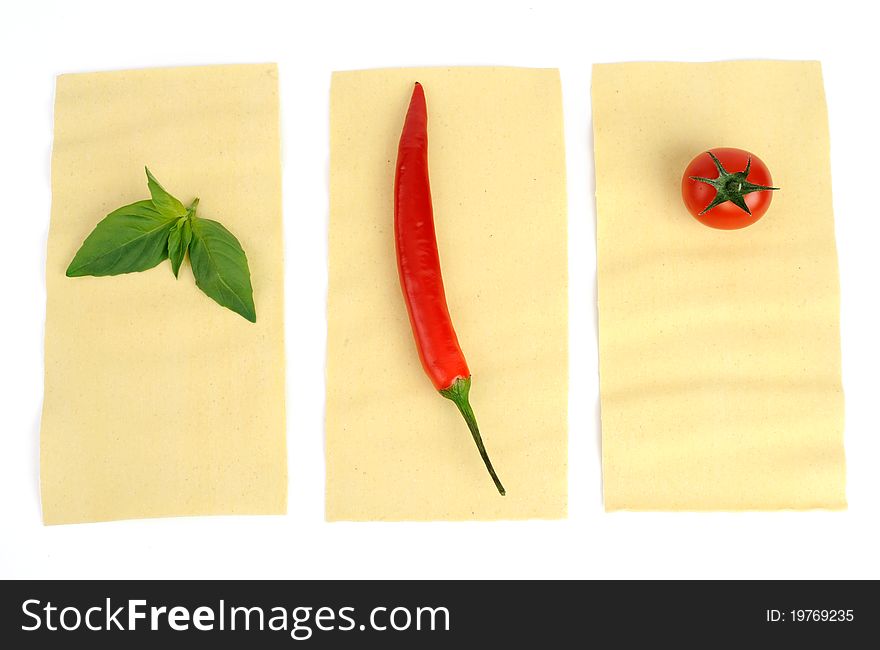 An image of basil, pepper and tomato on raw lasagna. An image of basil, pepper and tomato on raw lasagna