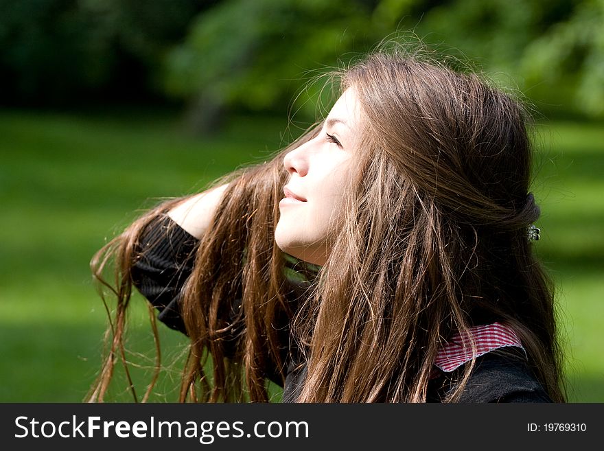 Beautiful girl in park is looking at the sun with luxurious hair. Beautiful girl in park is looking at the sun with luxurious hair