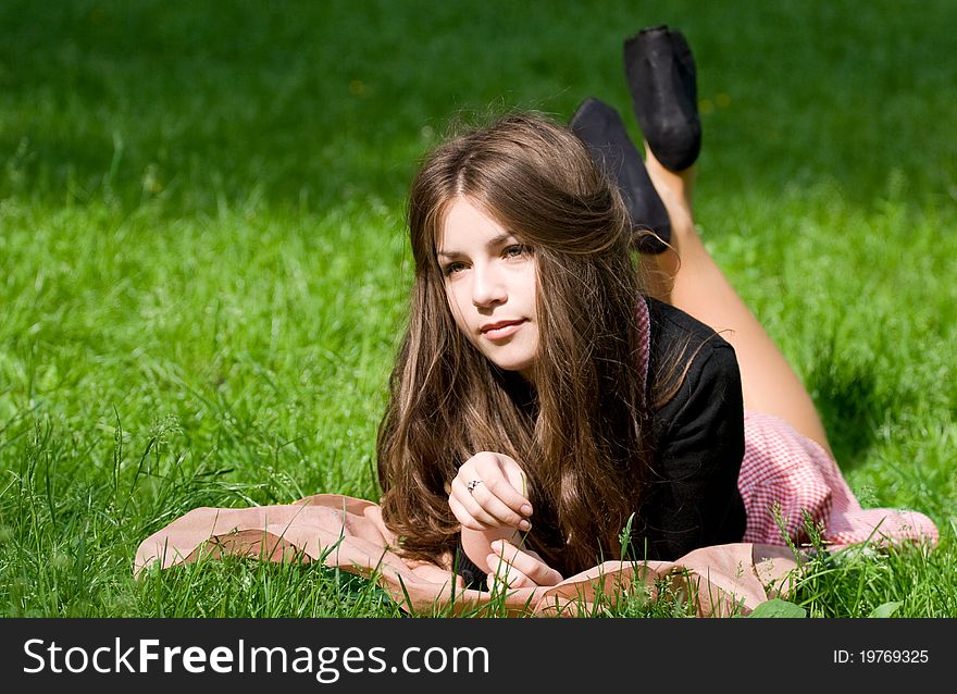 Attractive girl is lying on the grass in the park, starring to the infinity and thinking. Attractive girl is lying on the grass in the park, starring to the infinity and thinking