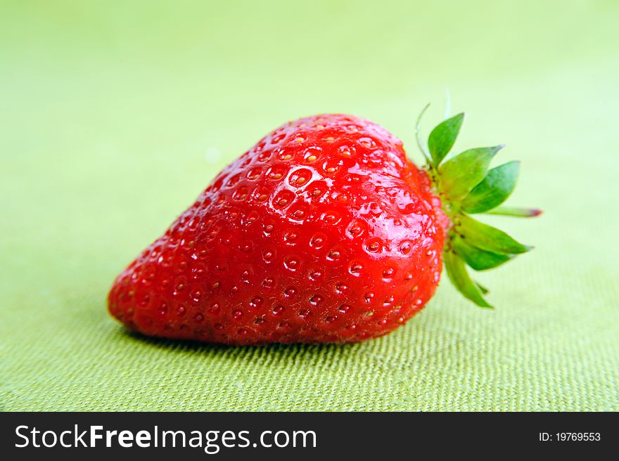 A fresh red strawberry on green background