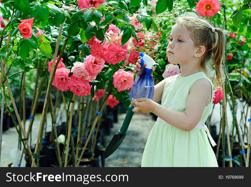 An image of a little girl watering flowers in a greenhouse