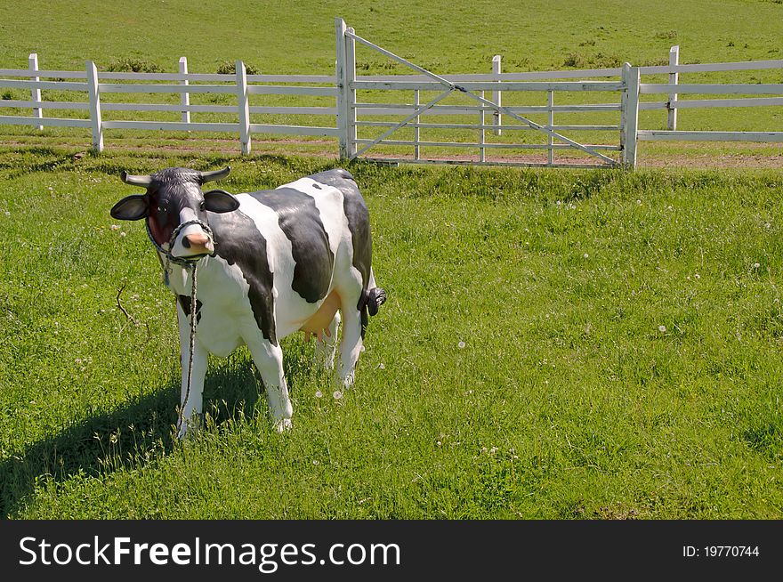 Artificial black spotted cow standing in the green grass. Artificial black spotted cow standing in the green grass