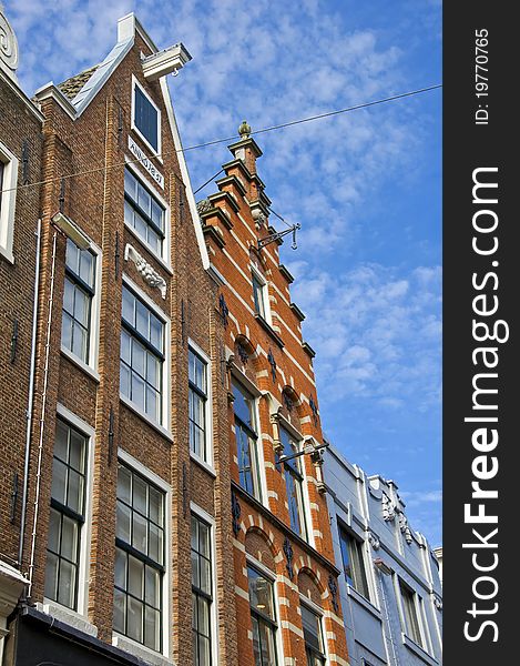 Amsterdam. Dutch houses with a hook at the blue sky. Urban environment of the historical city center.