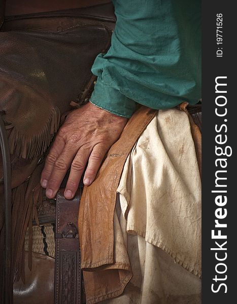 A cowboy's hand resting on his saddle. A cowboy's hand resting on his saddle