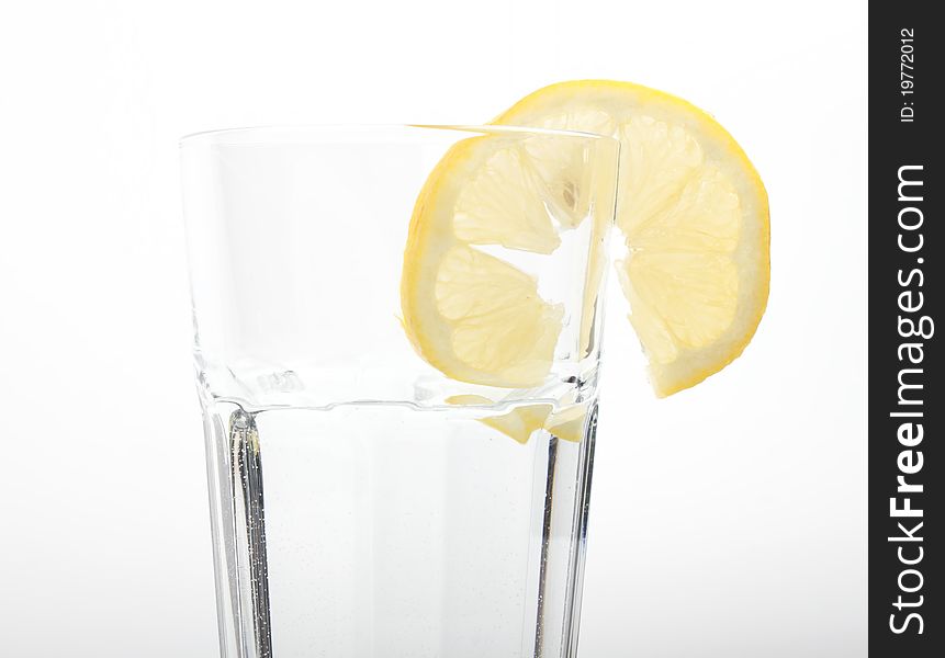 Mineral water in a glass with a lemon on a white isolated background. Mineral water in a glass with a lemon on a white isolated background