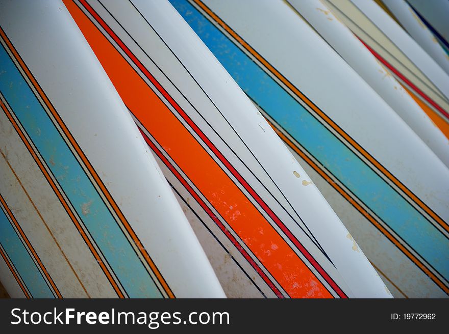 A row of sandy, striped beach surfboards with bright colors. A row of sandy, striped beach surfboards with bright colors