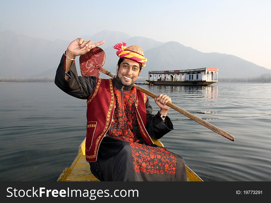 Pathani boy (North Indian) in tradition burqa dress sitting on a shikara boat singing hindi song with houseboat on Dal Lake, Kashmir as background. Pathani boy (North Indian) in tradition burqa dress sitting on a shikara boat singing hindi song with houseboat on Dal Lake, Kashmir as background