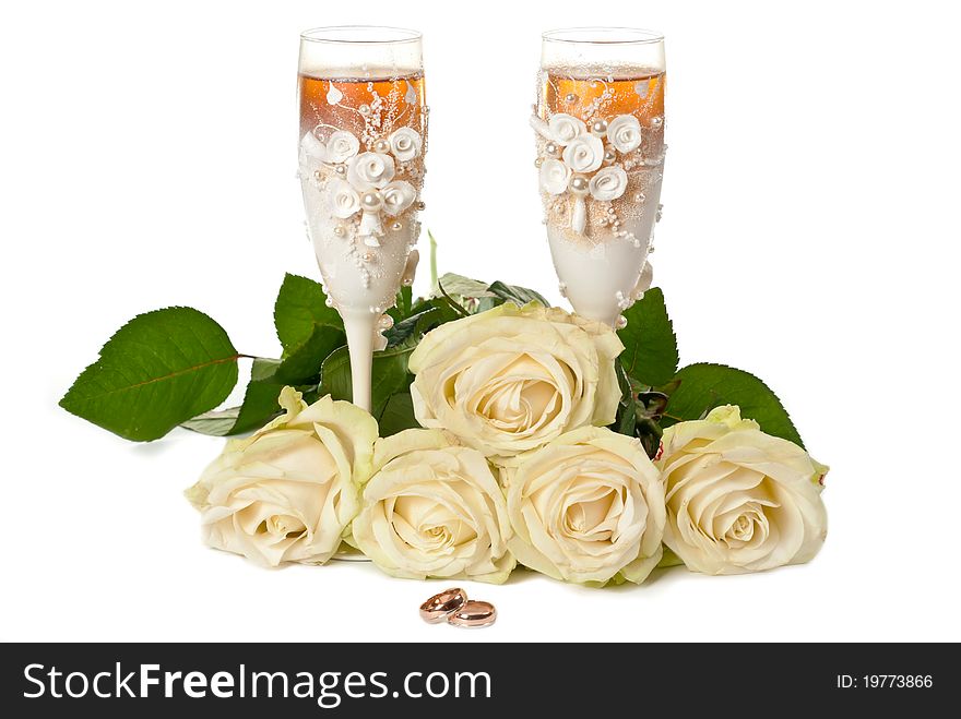 Two glasses of celebratory champagne with white roses and rings. Two glasses of celebratory champagne with white roses and rings