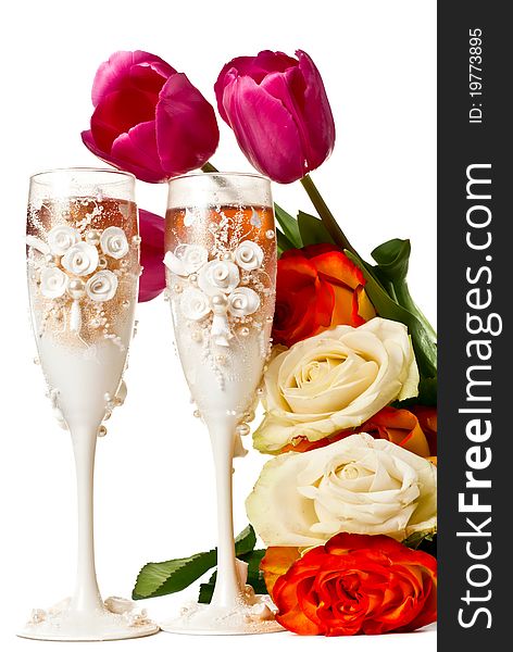 Two glasses of celebratory champagne with roses and tulips. Isolated on white. Two glasses of celebratory champagne with roses and tulips. Isolated on white