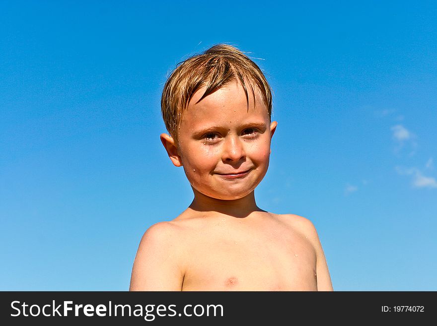 Portrait of cute boy at the beach with blue sky
