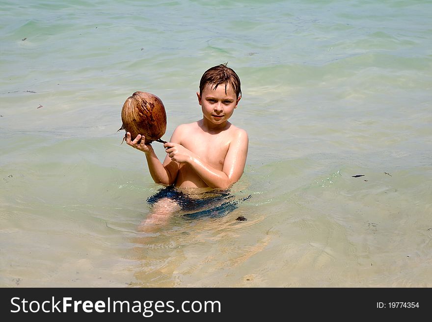 Boy is playing with a coconut on a beautiful beach