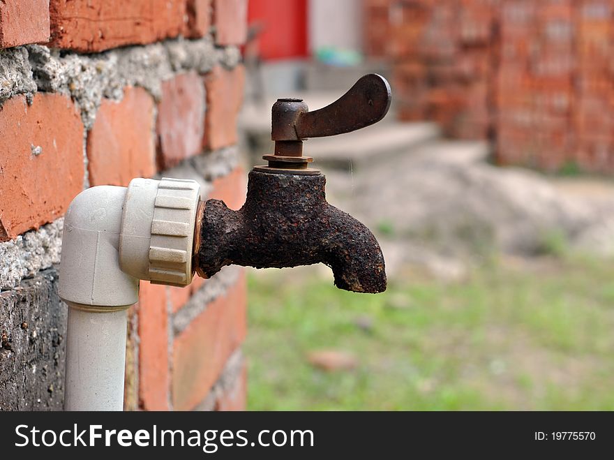 Close up of old metal water tap on brick wall