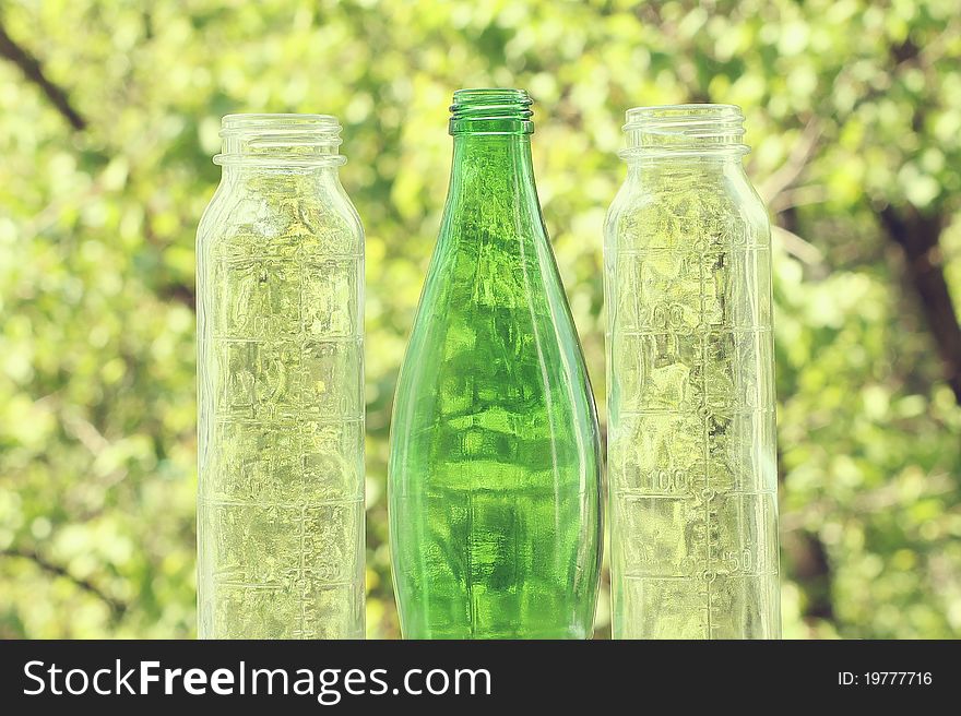 Three glass bottles on the background of trees