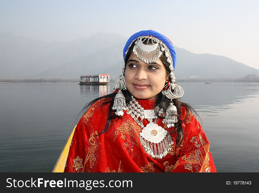 Very beautiful Kashmir girl in 20s looking at her side with a houseboat, hills and Dal Lake at Background. Very beautiful Kashmir girl in 20s looking at her side with a houseboat, hills and Dal Lake at Background