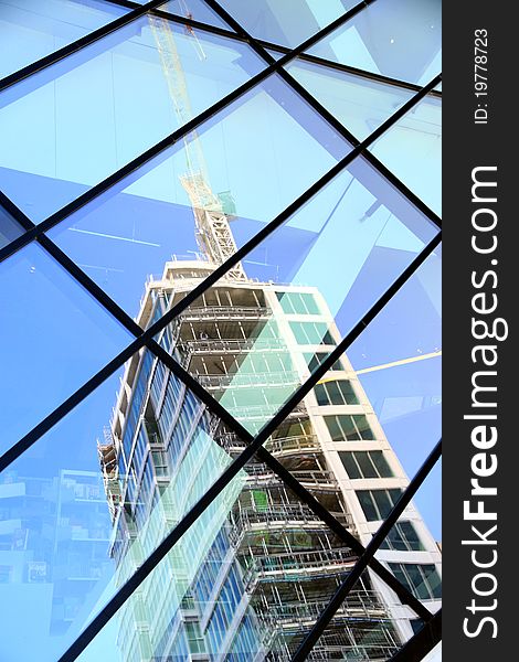 A building under construction reflected in a glass structure