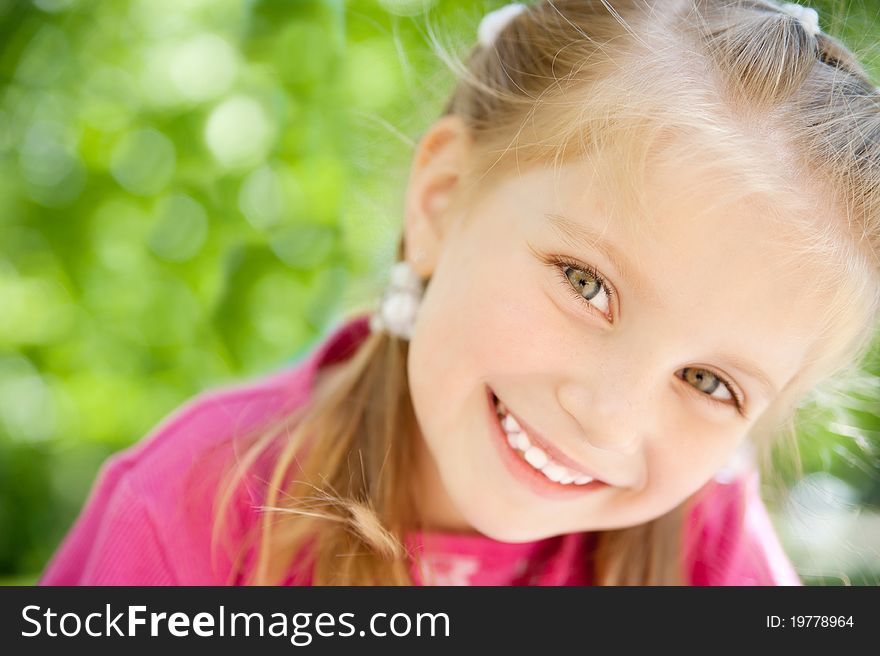 Cute little girl smiling in a park close-up