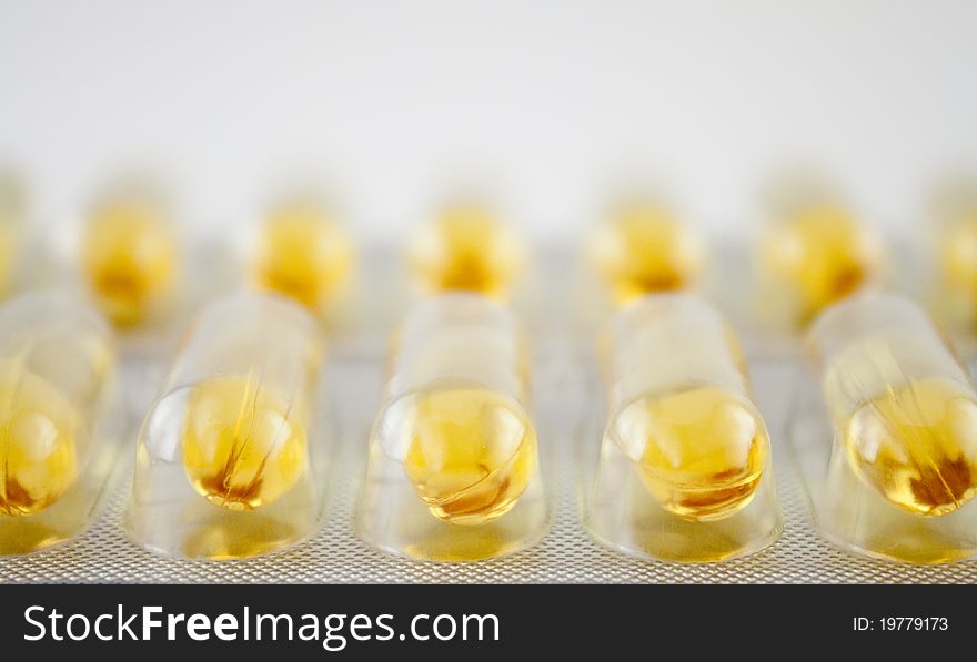 Plastic and foil blister with rows of yellow gel pills. Plastic and foil blister with rows of yellow gel pills