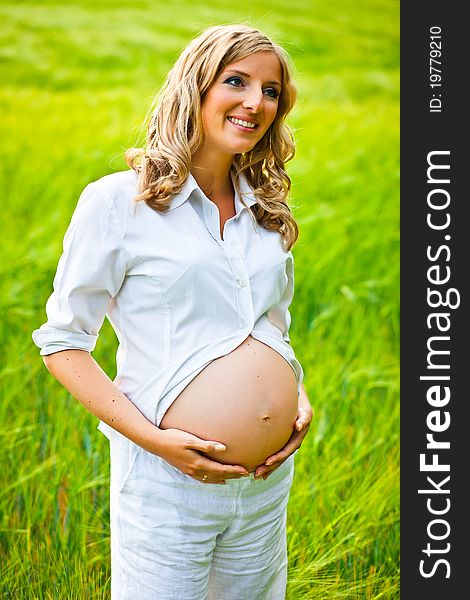 Pregnant woman outdoor on green wheat field