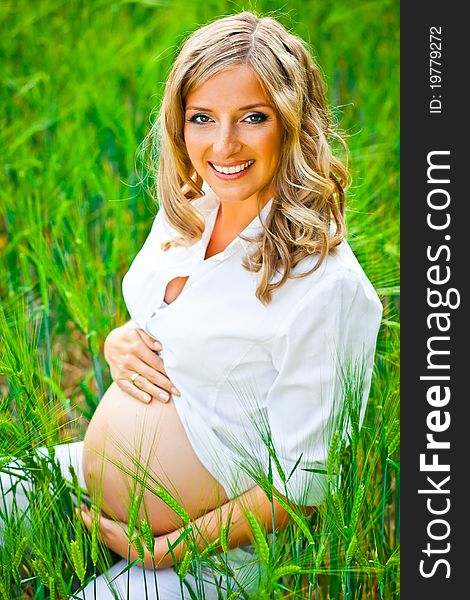 Pregnant woman outdoor on green field