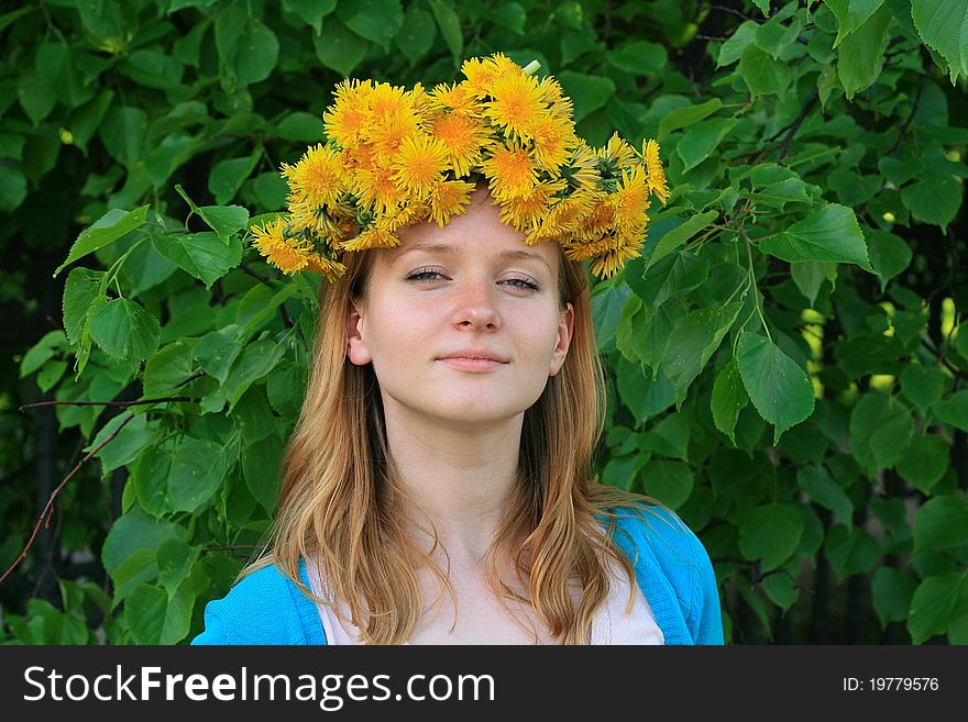 Young woman in wreath from yellow dandelions.