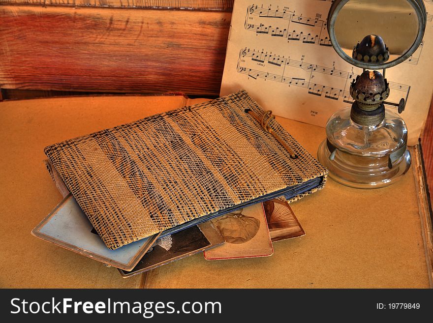 Old album and photos, oil lamp and note on wooden background. Old album and photos, oil lamp and note on wooden background.