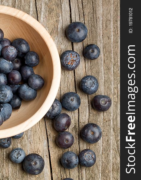 Top view on wooden bowl with fresh blueberry on old wooden table