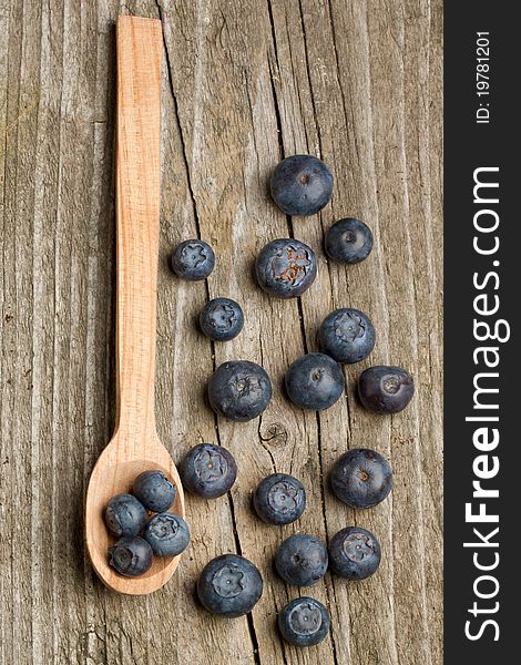 Top view on wooden spoon with fresh blueberries on old wooden table