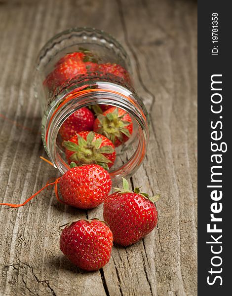 Glass pot of fresh strawberry on old wooden table