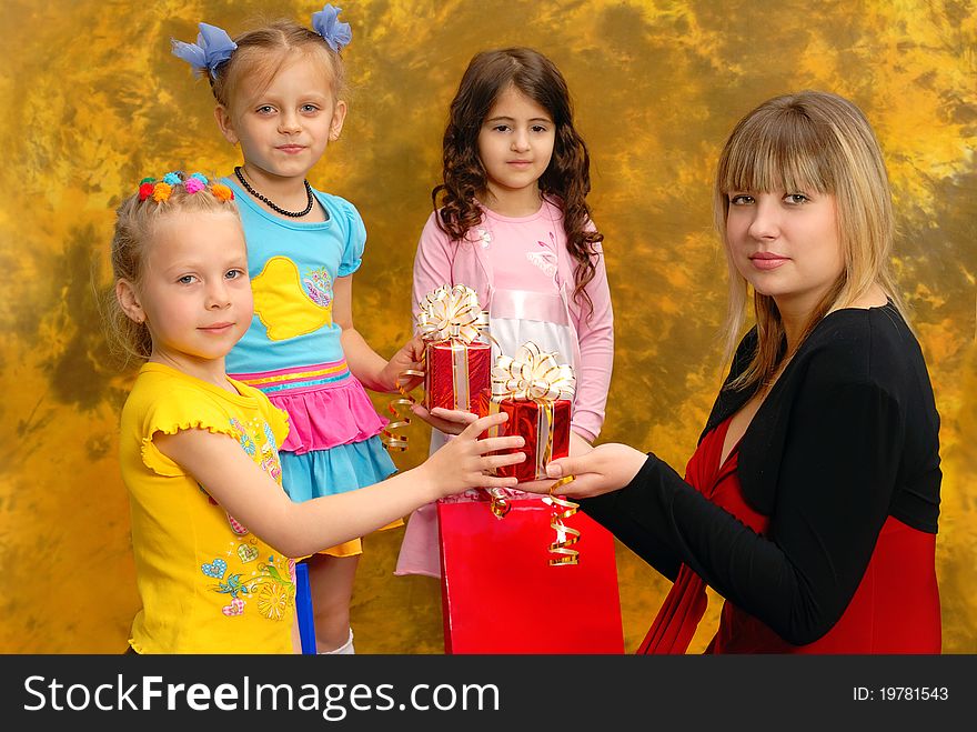Young beautiful woman give gifts to the little children. Abstract autumn background. Young beautiful woman give gifts to the little children. Abstract autumn background