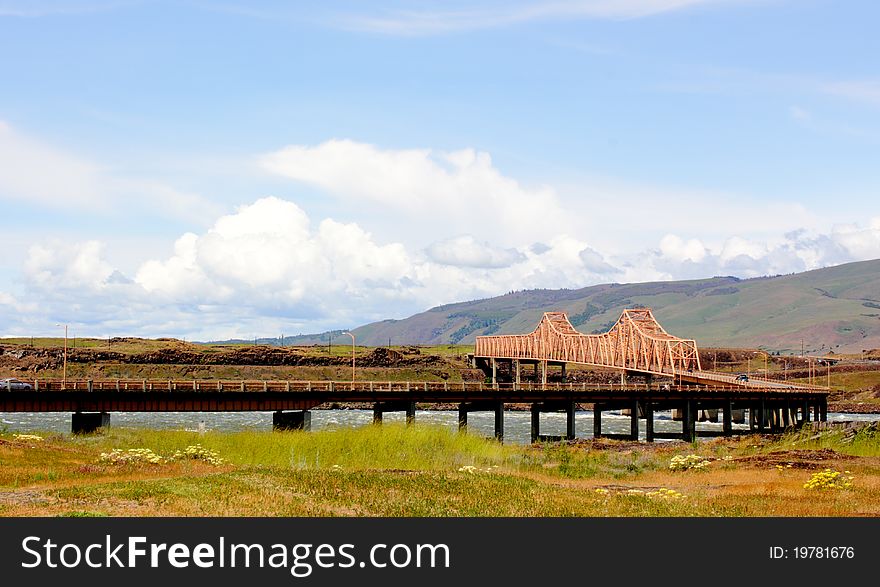 The Dalles Bridge over the Columbia River in the Columbia River Gorge with the rolling hills of eastern Washington in the background.